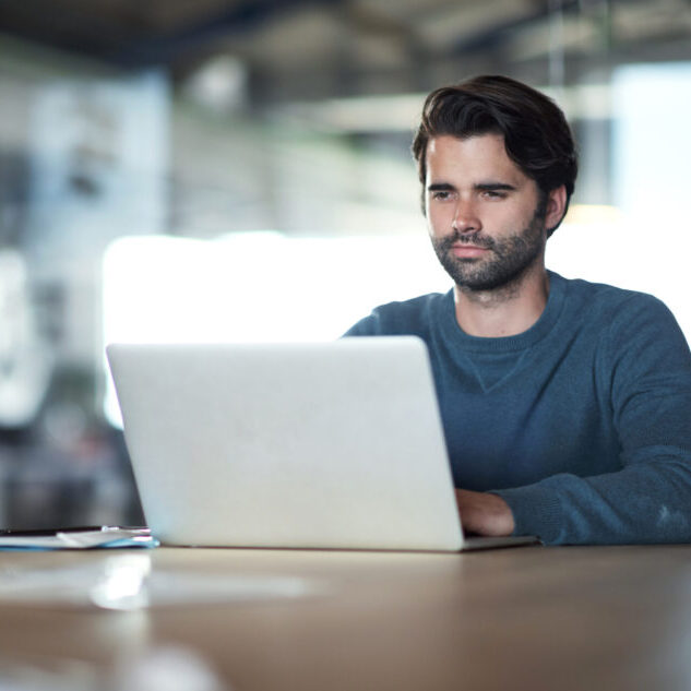 Shot of a young businessman using a laptop at work