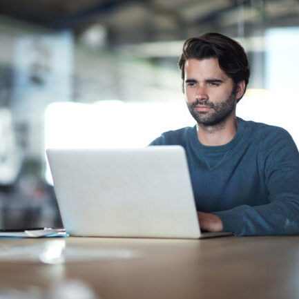 Shot of a young businessman using a laptop at work